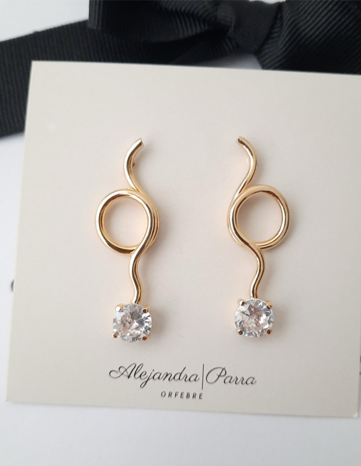 Gold Lola drop earrings featuring sparkling zirconia on a branded Alejandra Parra card.