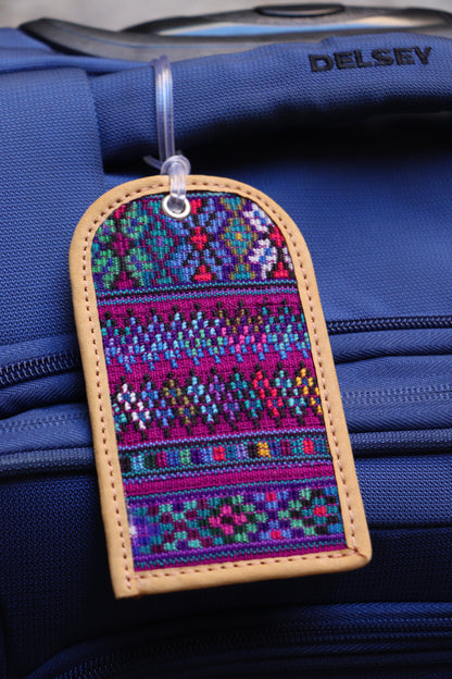 Colorful handwoven luggage tags crafted from from Huipil garments, with a sturdy plastic latch on a suitcase. 