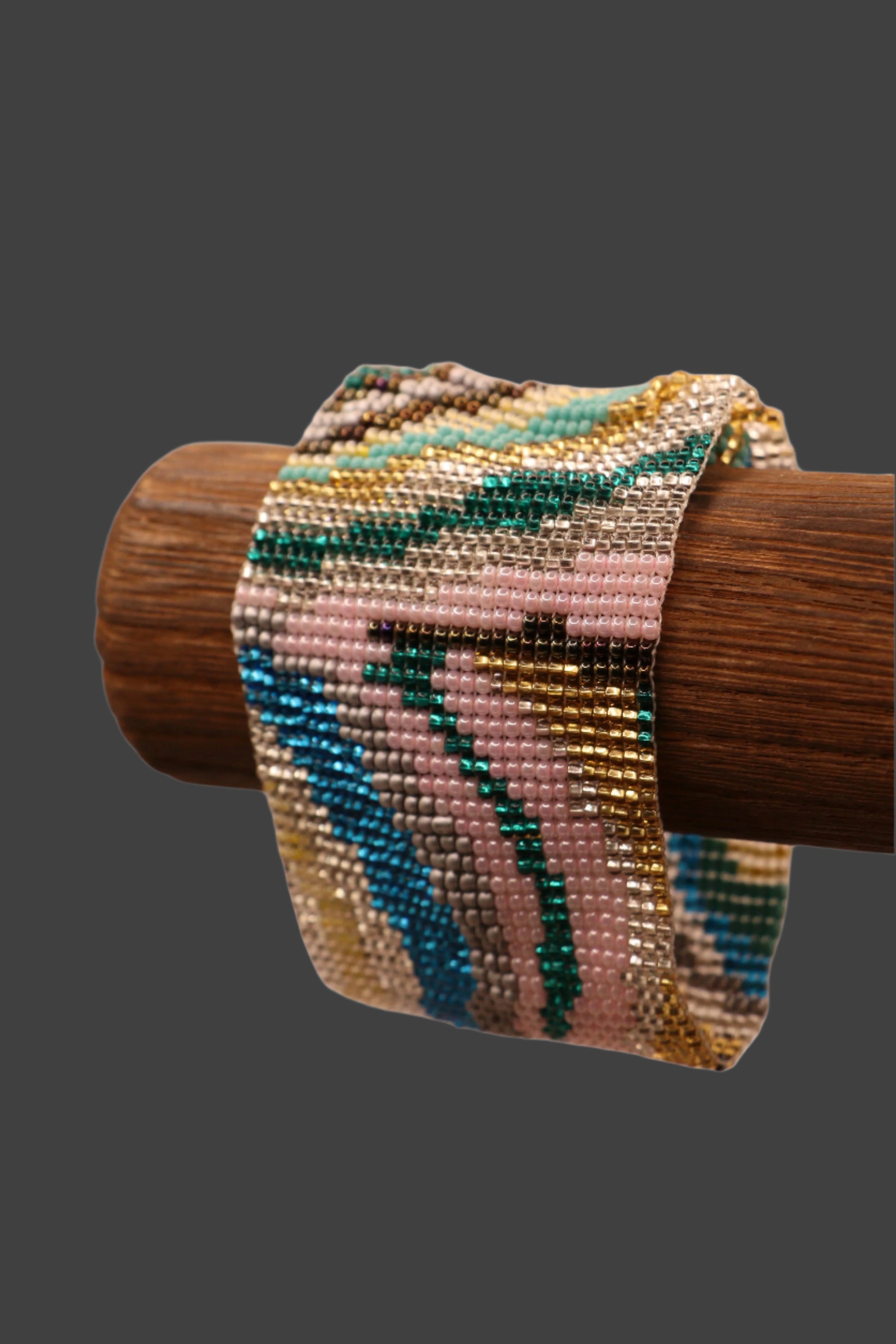 Handwoven multicolor beaded bracelet with geometric pattern displayed on wooden bracelet stand